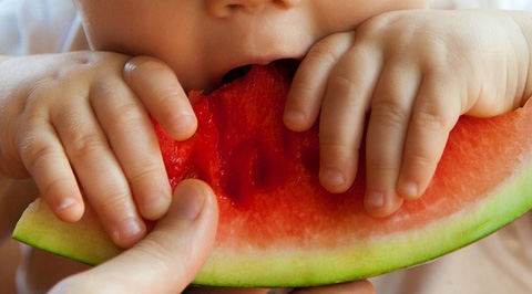 closeup van kindje dat in meloen bijt
